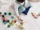 child in white long sleeve top and dungaree trousers playing with colorful lego blocks
