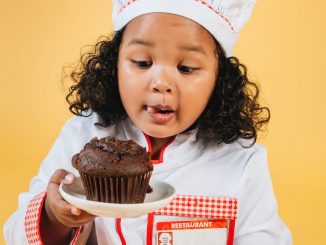 adorable little chef with muffin on plate in hand