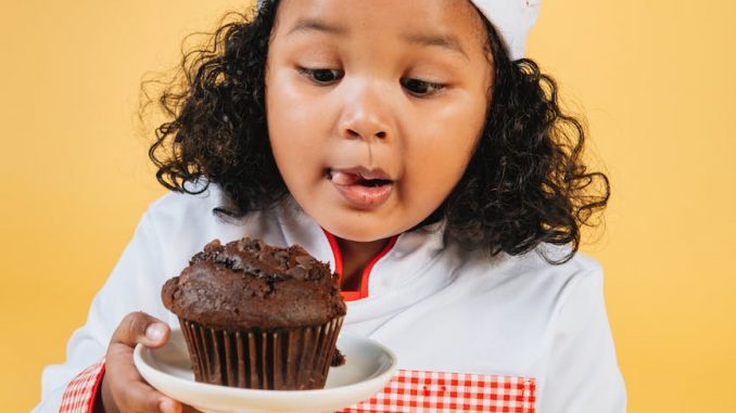 adorable little chef with muffin on plate in hand