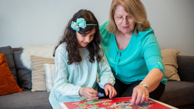 a woman putting together a jigsaw puzzle with her granddaughter