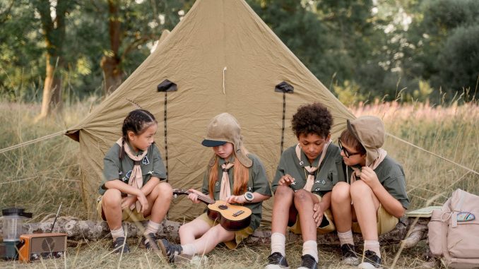 multiracial kids sitting beside tent