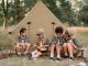 multiracial kids sitting beside tent