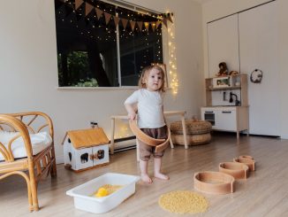 toddler girl playing with wooden shapes of different size and pasta while trying to put biggest shape on
