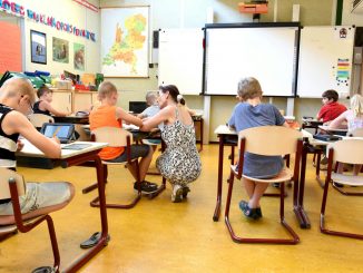 children sitting on brown chairs inside the classroom