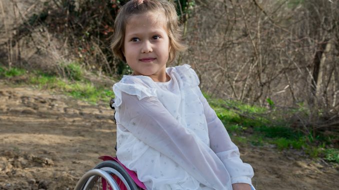 cheerful girl sitting in disabled carriage