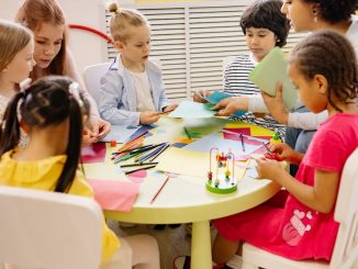children sitting on chairs in front of table with art materials