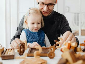 a man talking to his daughter while playing wooden toys on the table