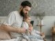 man in white shirt with a child sitting on the bed